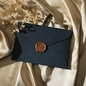 Navy blue linen envelope with vintage brown wax seal on elegant champagne silk fabric