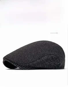 Close-up of gray wool flat cap with patchwork design and SMOWRIDS metal logo detail