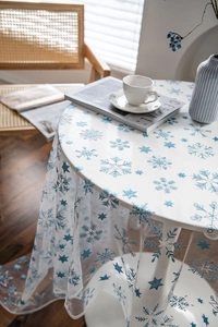Blue snowflake and star pattern sheer tablecloth on a white round table for home decor