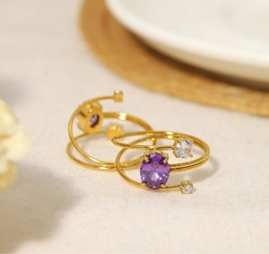 Detailaufnahme eines mehrlagigen goldenen Spiralrings mit ovalem violettem Zirkonia-Stein