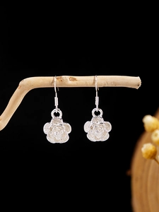 Macro shot of silver vintage flower earrings with layered petals on a wooden branch