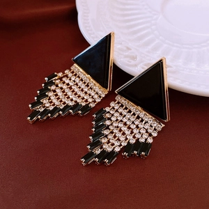 Detailed macro of gold tassel earrings with black triangles and shimmering rhinestones
