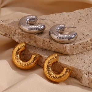 Detail showing gold and silver thick C-shape hoop earrings with hammered metal texture