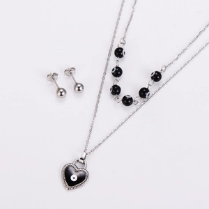 Detail of silver layering chain with black heart evil eye pendant and matching beads