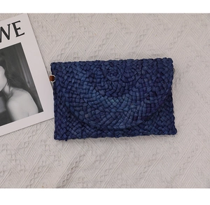 Vista dall'alto della pochette in paglia intrecciata blu navy su pizzo bianco