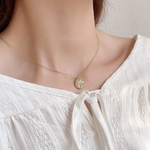 Elegant gold round textured relief pendant necklace shown on a female model neck