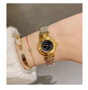 Close-up of elegant gold steel watch with black dial and Roman numerals on female wrist