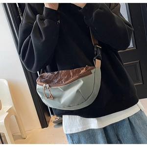 Detail of grey-green nylon crossbody bag worn across the chest with brown contrast texture