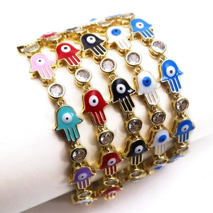 Detail view of colorful Hamsa and Evil Eye charms with zircon settings on gold chain