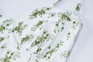 Detalle de la parte superior blanca con estampado floral verde y escote plisado