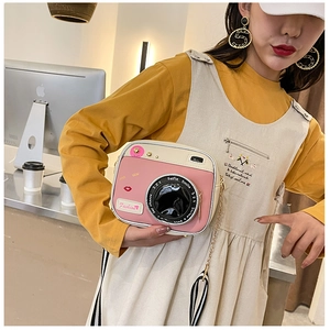 Close-up of creative pink camera-shaped crossbody bag with dual straps and fashion lens detail