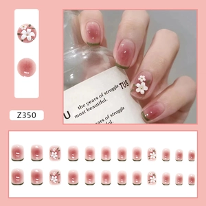 Close-up of pink gradient press-on nails with 3D white daisy floral patterns and French tips