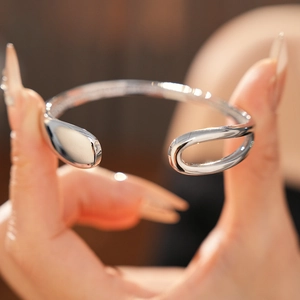 Detailed view of silver water drop hollow bangle with smooth polished metal finish