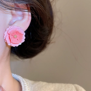 Vue rapprochée de boucles d'oreilles fleurs roses en résine portées par un mannequin