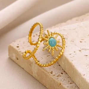 Detailed side view of bohemian gold sunburst ring with green stone on stone surface