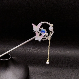 Vue détaillée d'épingle à cheveux papillon argentée avec pompons roses et perles