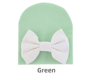 Detail of mint green knit baby hat with a soft texture and a large white bow decoration
