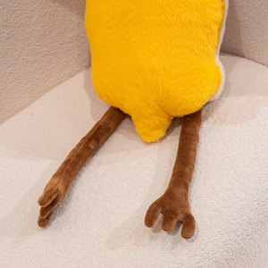 Detail shot of a soft yellow pterosaur plush toy resting on a textured cream sofa.