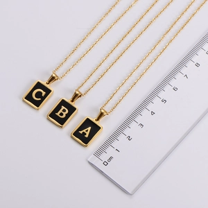 Detail view of gold square letter pendants with size ruler measuring 1.5cm width