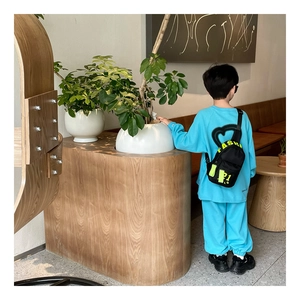 Sac de poitrine noir pour enfant avec tenue bleue décontractée et baskets noires