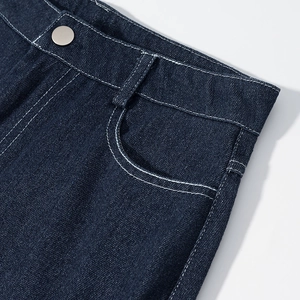 Détail d'un jean en denim bleu foncé avec bouton métallique argenté et coutures blanches