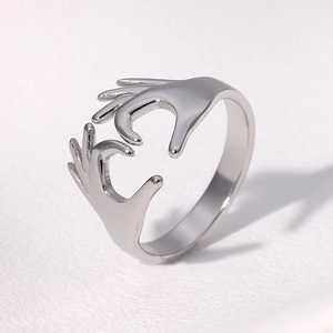 Detail of silver heart-shaped hands adjustable ring with a polished metallic finish
