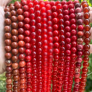 Polished natural red stone beads held in hand for jewelry making with natural background