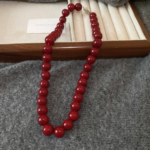 Detail of dark red glass bead necklace with high-gloss finish and silver buckle clasp