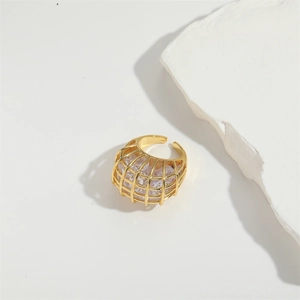 Close-up of gold metal ring featuring embedded clear zircons on a white minimalist base