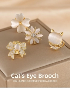 Close-up of four-leaf clover and bow cat's eye stone brooches on champagne silk background