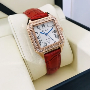 Detail of square rose gold watch with red leather strap, diamond bezel and Roman numerals