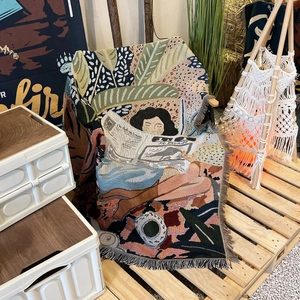 Detail of bohemian outdoor camping blanket featuring woven illustration and fringe edges
