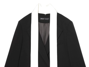 Detail of minimalist black blazer showing contrast white lapel and woven size label