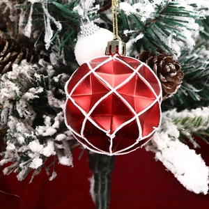 Detail of red faceted Christmas ball with white glitter snow on snowy tree branch