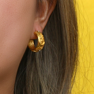 Close-up of 18K gold-plated C-shaped hoop earring with celestial sun and moon relief patterns