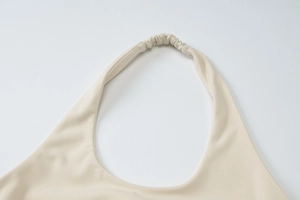 Gros plan détaillé du décolleté licou beige présentant la texture du tricot froncé élastique