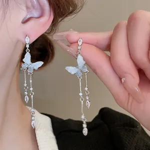 Detail of silver drop earrings with blue gradient butterfly and sparkling rhinestones