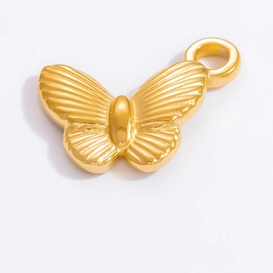 Macro shot of gold bow-shaped pendant with detailed wing texture and metallic finish