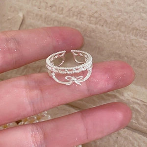 Détail d'une bague nœud en argent ajouré avec texture dentelle portée au doigt