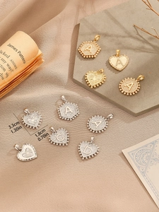 Detailed view of gold and silver initial pendants with bead edges and star patterns