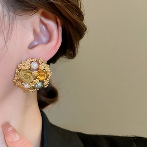 Detailed close-up of retro floral stud earring with pearls and amber gemstone on ear