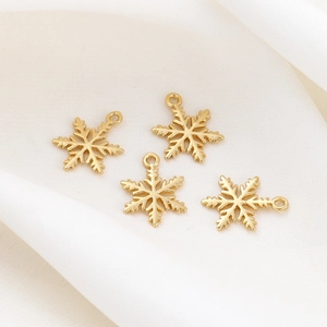 Close-up of four 18K gold snowflake pendants for DIY jewelry on white silk fabric