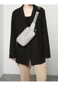 Gray quilted waist bag worn by a model in a black blazer, featuring adjustable strap