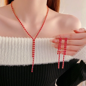 Detail view of red gemstone water drop tassel necklace and earrings set on model