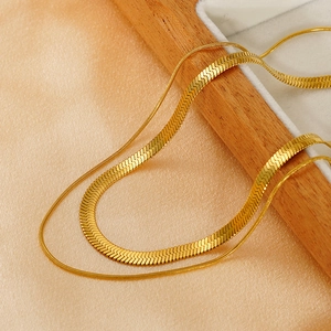 Macro shot of gold double layered snake chain necklace on soft orange silk fabric