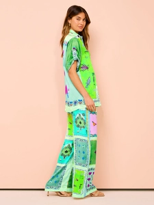 Detail view of stylish green print two-piece set featuring satin shirt and wide-leg trousers