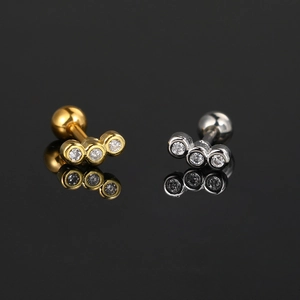 Zircon geometric stud earrings in gold and silver finish on a sleek black surface