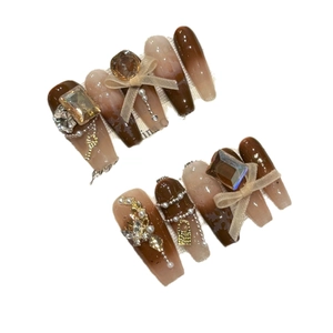 Handmade brown marble press-on nails with bow, rhinestones and pearls on white background