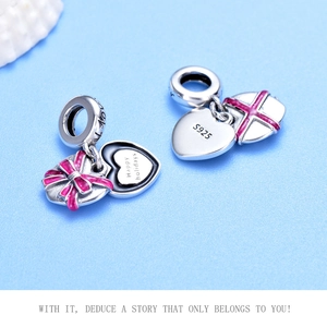 Macro shot of 925 silver heart charm with pink enamel bow and Happy Holidays engraving