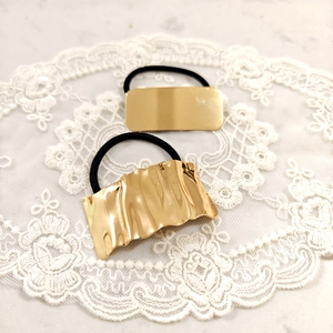 Detailed view of gold textured star hair ties on elegant white lace and marble surface